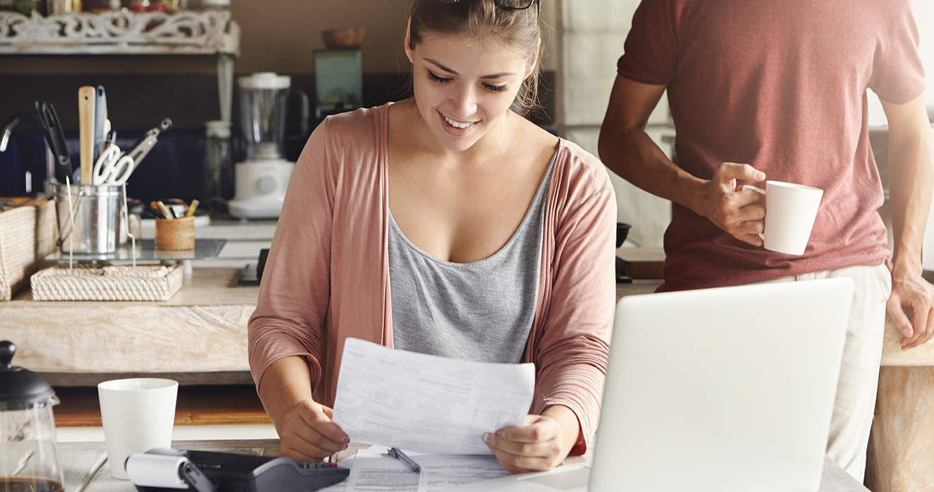 A solar battery system allows you to take control of your bills and maximize your solar savings. A girl is smiling at her the solar savings while reading her utility bill.